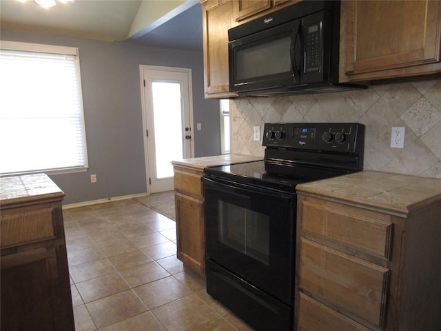 kitchen featuring tile countertops, baseboards, light tile patterned floors, backsplash, and black appliances