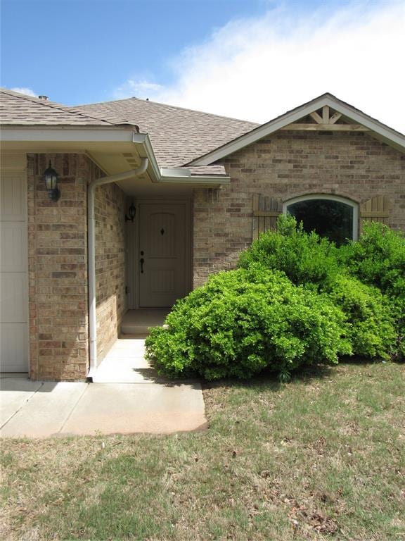 900 Aspen Creek Ter, Yukon, OK 73099 - doorway to property featuring roof with shingles, brick siding, and an attached garage