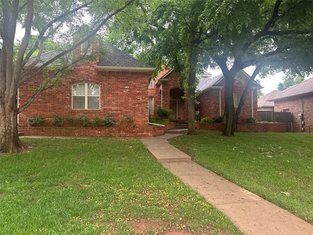 view of front of property with roof with shingles, a front lawn, and brick siding