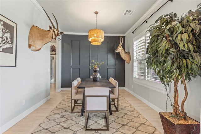dining space with light wood-style flooring, ornamental molding, and baseboards