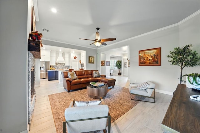 living room with ceiling fan, ornamental molding, light wood finished floors, and baseboards