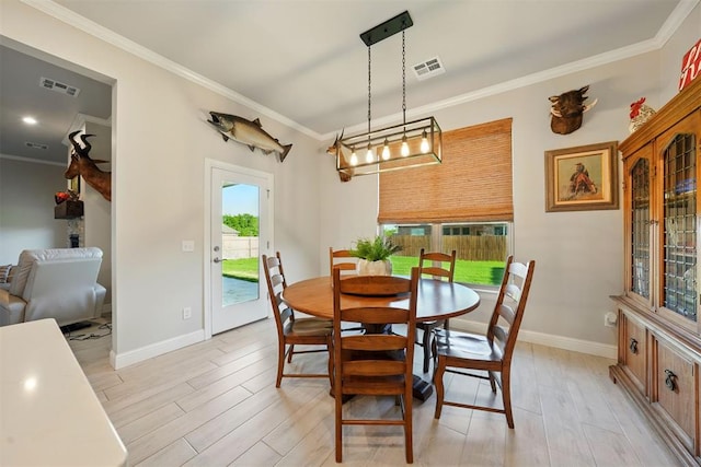 dining room featuring light wood-type flooring, crown molding, and baseboards