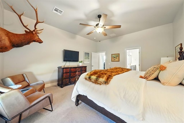 bedroom featuring light carpet, baseboards, ceiling fan, and ensuite bath