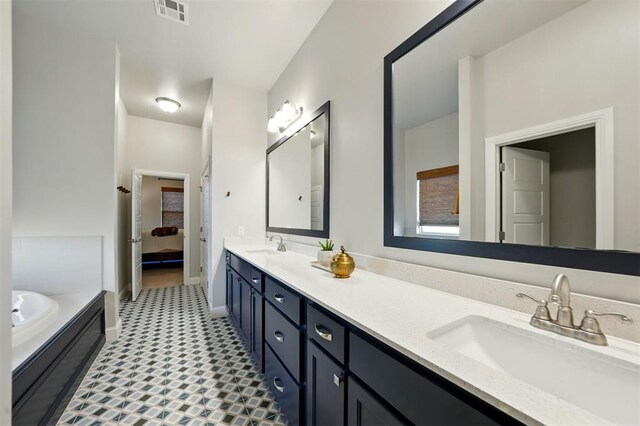 bathroom with double vanity, a bath, baseboards, and ensuite bathroom