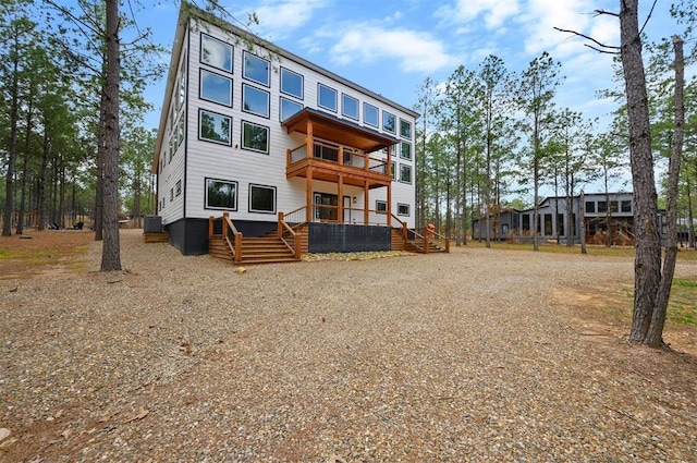 back of property with a wooden deck and a balcony