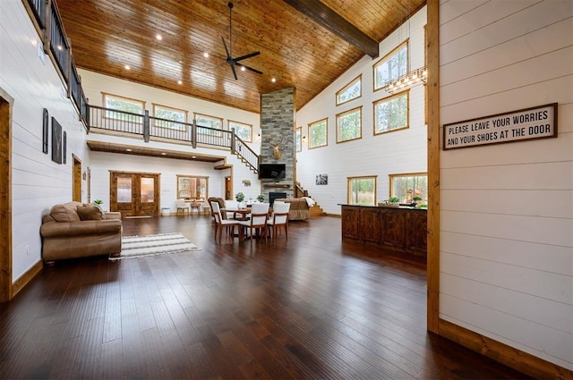 living area featuring high vaulted ceiling, baseboards, a ceiling fan, and wood walls