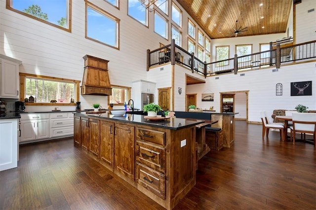 kitchen featuring a large island, a high ceiling, dark wood finished floors, and dark countertops