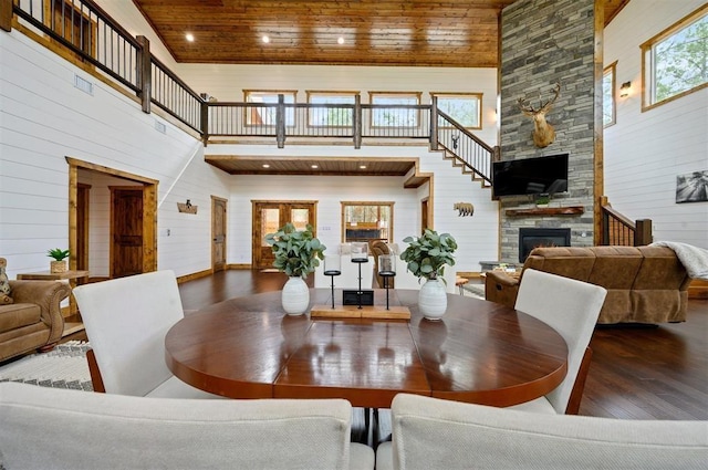 dining area featuring wooden ceiling, a high ceiling, a fireplace, and wood finished floors