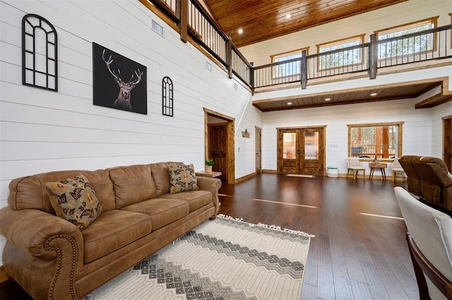 living room with french doors, a towering ceiling, wooden ceiling, wood-type flooring, and wooden walls