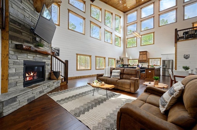 living room featuring a fireplace, a healthy amount of sunlight, wood-type flooring, and a towering ceiling