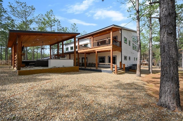 back of house with ceiling fan, a deck, and a balcony