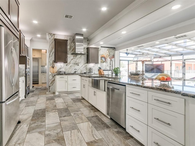 6363 NW 220th St, Edmond, OK 73025 - kitchen with wall chimney exhaust hood, visible vents, backsplash, crown molding, and appliances with stainless steel finishes