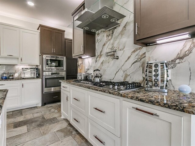 6363 NW 220th St, Edmond, OK 73025 - kitchen with white cabinets, ventilation hood, dark stone countertops, tasteful backsplash, and appliances with stainless steel finishes