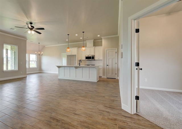 3404 Slate River Dr, Yukon, OK 73099 - kitchen with stainless steel microwave, open floor plan, ornamental molding, ceiling fan, and baseboards