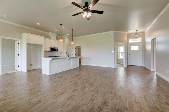 3404 Slate River Dr, Yukon, OK 73099 - kitchen featuring stainless steel microwave, open floor plan, light countertops, ornamental molding, and baseboards