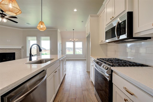 3404 Slate River Dr, Yukon, OK 73099 - kitchen featuring appliances with stainless steel finishes, a sink, ceiling fan, a fireplace, and backsplash