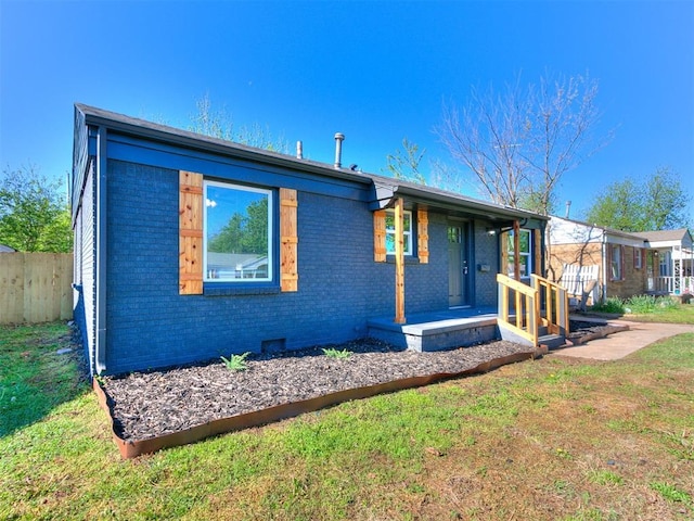 view of front of property featuring brick siding, fence, a front yard, and covered porch