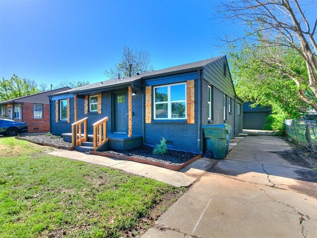 view of front of home featuring fence, driveway, a front lawn, and brick siding