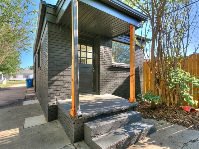 entrance to property with brick siding and fence