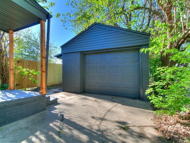 detached garage with concrete driveway and fence