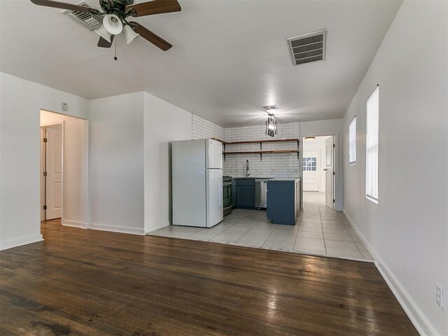 kitchen with light wood finished floors, stainless steel appliances, open shelves, visible vents, and a ceiling fan