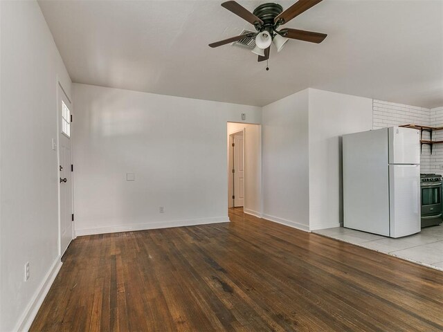 unfurnished living room featuring hardwood / wood-style floors, a ceiling fan, and baseboards