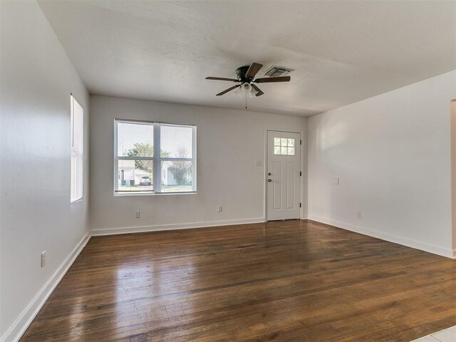 interior space with hardwood / wood-style floors, a ceiling fan, baseboards, and visible vents