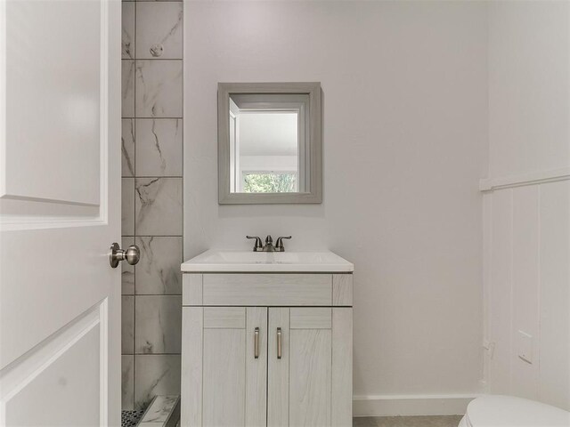 bathroom with toilet, vanity, and baseboards