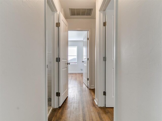 hall with baseboards, visible vents, and dark wood finished floors