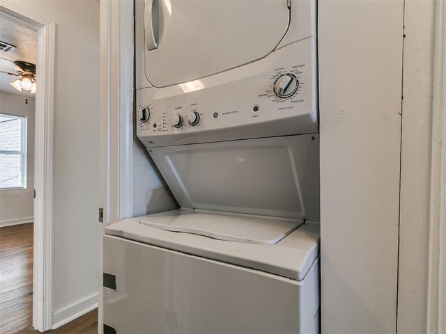 laundry area with baseboards, stacked washer / drying machine, wood finished floors, and laundry area