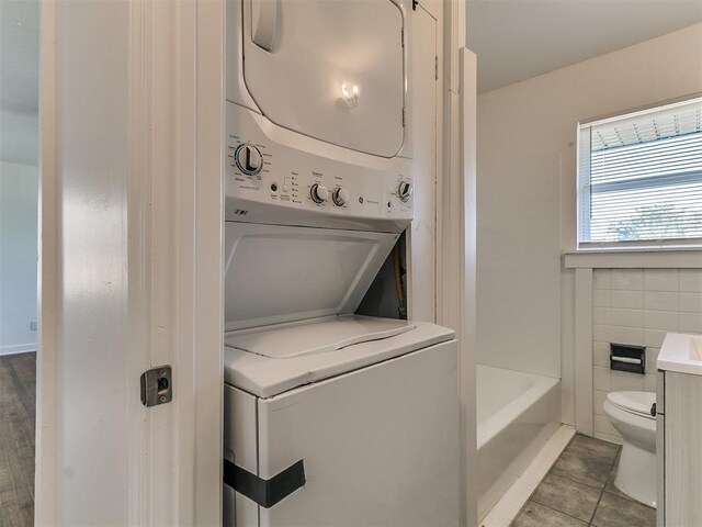 washroom featuring tile patterned flooring, stacked washing maching and dryer, and laundry area