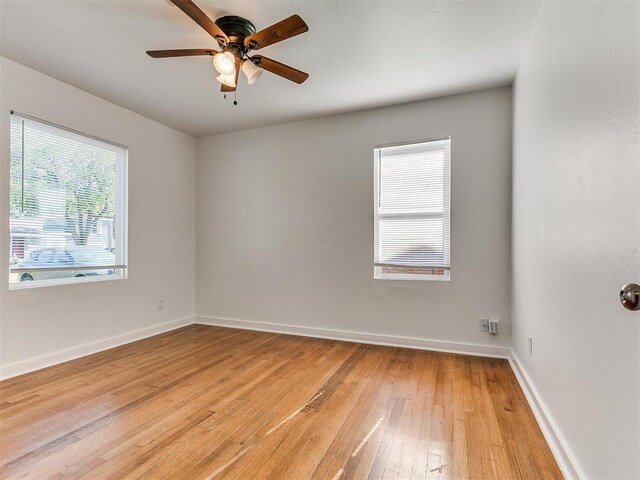 unfurnished room with a ceiling fan, baseboards, and light wood-style floors