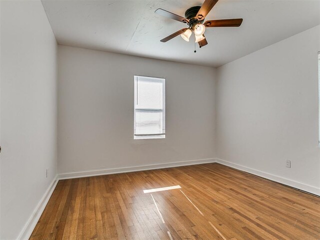 empty room featuring baseboards, hardwood / wood-style flooring, and ceiling fan