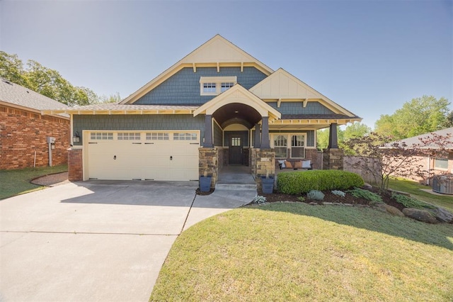 4940 Sonny Blues Pl, Edmond, OK 73034 - craftsman house featuring concrete driveway, covered porch, stone siding, a front yard, and a garage