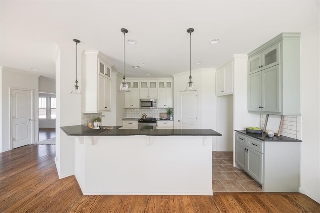 4940 Sonny Blues Pl, Edmond, OK 73034 - kitchen featuring dark countertops, a peninsula, backsplash, and appliances with stainless steel finishes