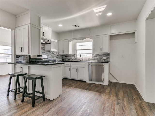 603 N Madison Ave, Blanchard, OK 73010 - kitchen with dark countertops, appliances with stainless steel finishes, under cabinet range hood, dark wood-type flooring, and visible vents