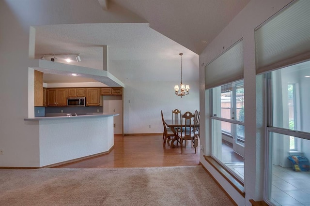 1117 Blue Ridge Dr, Edmond, OK 73003 - kitchen featuring stainless steel microwave, light colored carpet, brown cabinetry, a chandelier, and baseboards