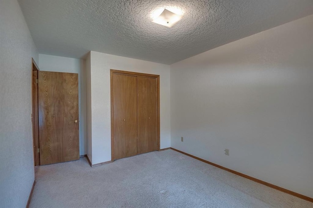 1117 Blue Ridge Dr, Edmond, OK 73003 - unfurnished bedroom with a closet, light carpet, baseboards, and a textured ceiling
