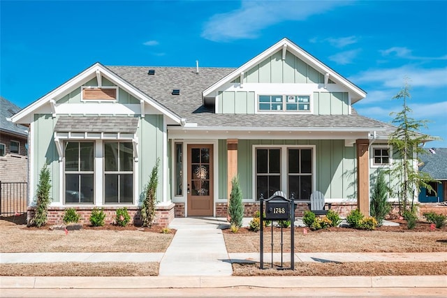 craftsman inspired home with board and batten siding, roof with shingles, and a porch