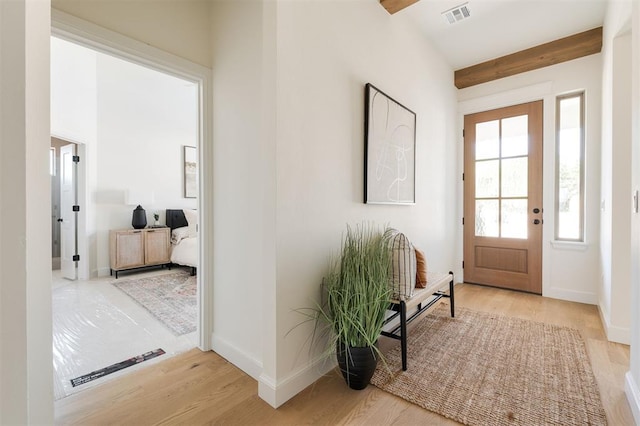 entryway featuring baseboards, wood finished floors, visible vents, and beam ceiling