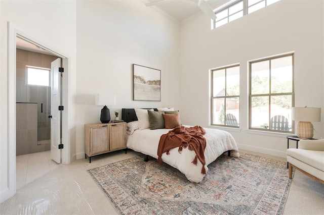 carpeted bedroom featuring connected bathroom, baseboards, a towering ceiling, and multiple windows