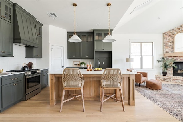 kitchen featuring stainless steel range with gas cooktop, light wood-style flooring, visible vents, and custom range hood