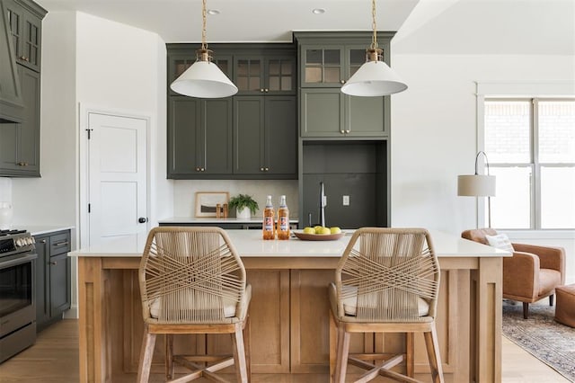 kitchen featuring glass insert cabinets, light countertops, a kitchen island, and stainless steel gas range