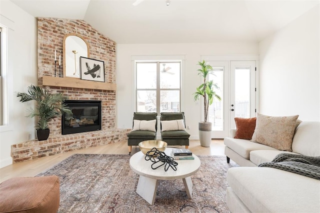 living area featuring vaulted ceiling, wood finished floors, and a fireplace