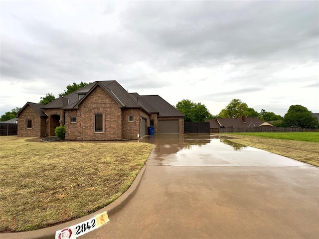 view of front of property with a front lawn, concrete driveway, brick siding, and a garage