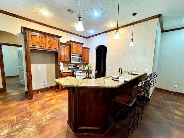kitchen with stainless steel appliances, crown molding, a textured wall, a peninsula, and arched walkways