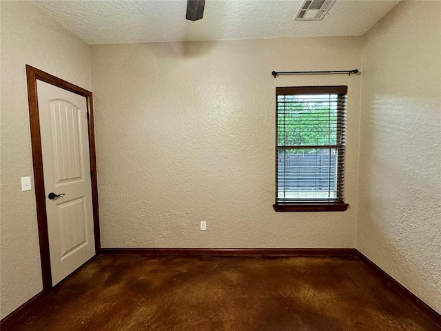 spare room featuring baseboards, visible vents, concrete flooring, and a textured wall