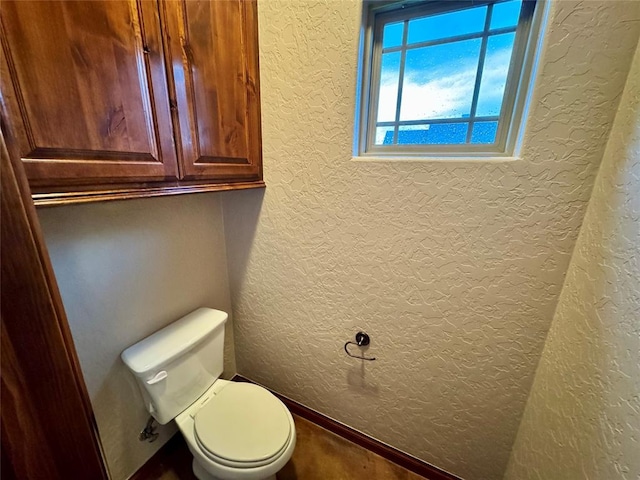 bathroom with toilet and a textured wall