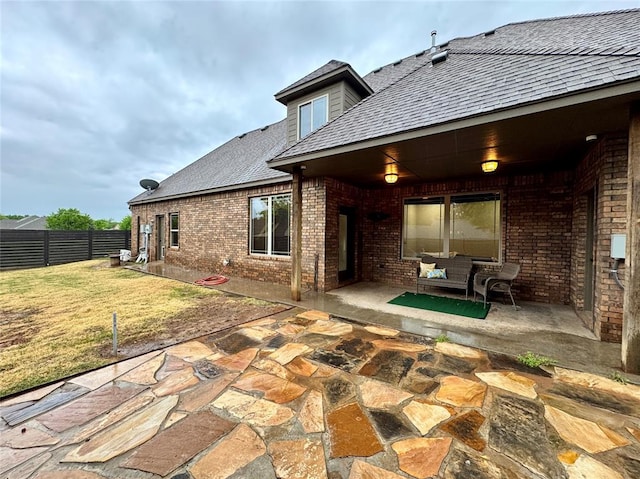 back of house featuring a patio, brick siding, fence, and a yard