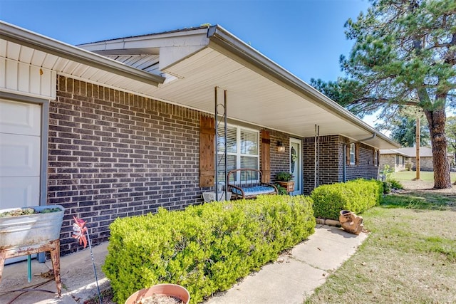 view of exterior entry with covered porch and brick siding